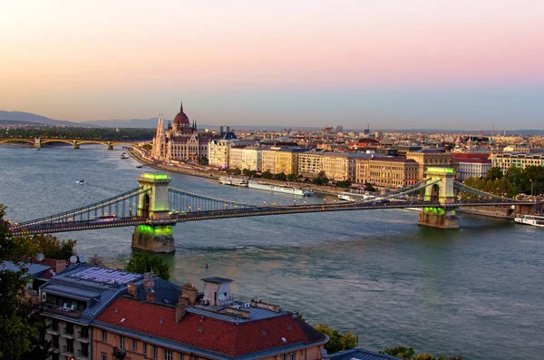 Vista aérea del paisaje nocturno de Budapest. Pintoresca puesta de sol en Budapest. Pintoresca vista del Puente de Cadena iluminado sobre el río Danubio y el edificio del Parlamento húngaro en el fondo — Foto de Stock