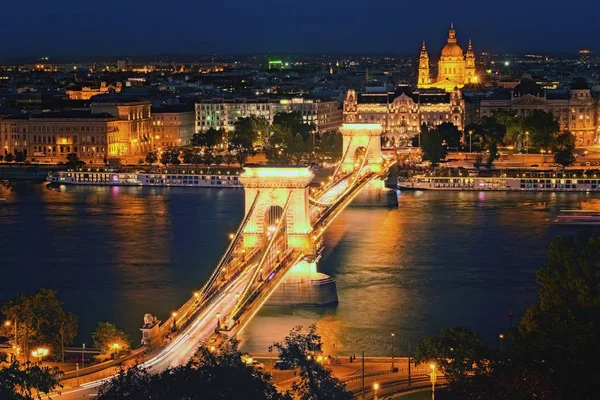 Vista panorámica nocturna de Budapest. Puente de la Cadena iluminado reflejado en el río Danubio. Edificios medievales iluminados a lo largo del terraplén del río. Concepto de viajes y turismo. Budapest, Hungría — Foto de Stock