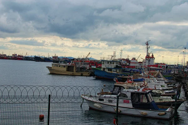 Istambul, Turquia-03 de janeiro de 2020: Porto com barcos de pesca ancorados e navios em Istambul. homem zarpa em seu barco. A paisagem urbana ao fundo. Céu de inverno dramático. Istambul, Turquia — Fotografia de Stock