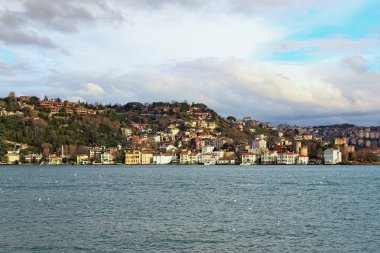 Boğaz (İstanbul Boğazı veya Boğazı) yakınlarındaki tepedeki konutların resimli manzarası. Şehrin üzerinde bulutlar var. İstanbul, Türkiye 'de kış günü