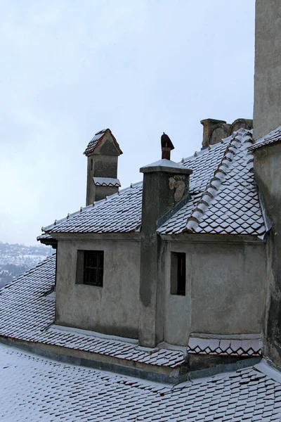 雪の中で赤い瓦の屋根の詳細なビュー。古代ブラン城、ドラキュラの城とも呼ばれる。ルーマニアの有名な観光地と旅行先 — ストック写真