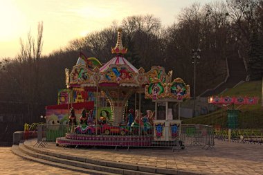 Kyiv, Ukrayna-Mart 01.2020: Sabah gündoğumu sırasında peri masalı kahramanlarıyla birlikte resim niteliğindeki klasik atlıkarıncayı yakın çekim. Halkın Dostluk Kemeri. Arka planda erken bahar renkleri.