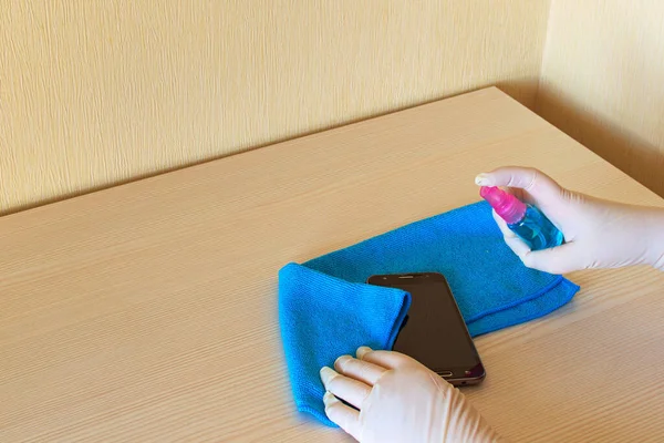 Woman's hands in medical gloves wipe smartphone screen by sanitizer liquid. Cleaning mobile phone for Covid-19 disease prevention. Disinfectant on wipes of phone for safety. Medical equipment.