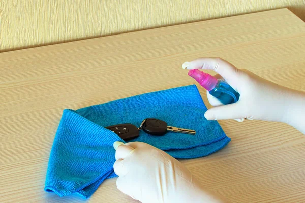 Woman's hands in medical gloves wipe car key by sanitizer liquid. Cleaning key  for Covid-19 disease prevention. Disinfectant on wipes of car key for safety. Medical equipment. Protection concept.