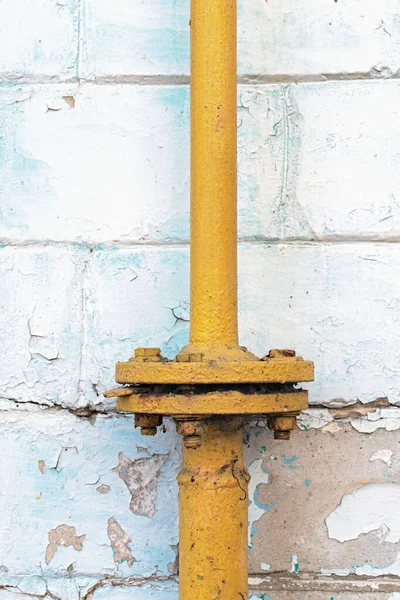 带有法兰连接的旧黄色煤气管道的特写视图 剥皮墙上的白砖 摘要背景 — 图库照片