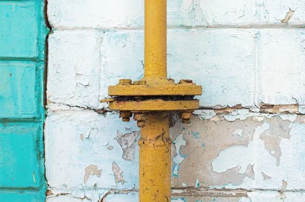 一个有法兰连接的黄色的旧煤气管道 剥皮墙上的白砖 摘要背景 — 图库照片