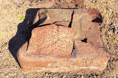 Eski paslı bir bidona yakın çekim. Eski paslı metal yüzey ve yerde yosun var. Pas, bidonun dibini mahvetmiş. Doku ya da arka plan. Soyut metalik arkaplan.
