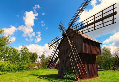 Bahar güneşli bir günde eski ahşap rüzgar değirmeninin klasik geniş açılı görüntüsü. Beyaz bulutlu mavi gökyüzü arkaplanı. Antik Ukrayna 'nın tarihi binaları kavramı.