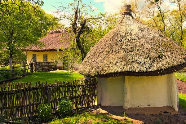 日当たりの良い日にはウィッカーフェンスに囲まれた庭園と茅葺き屋根の下の古代の粘土の家の広い角度の風景 古代ウクライナの歴史的建造物 ウクライナ ペレイスラフの民俗建築と生活の野外博物館 — ストック写真