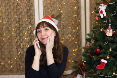 Noel Baba da telefonda konuşurken şapkalı kız. 