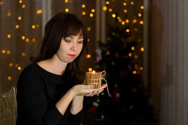 Menina segurando uma vela perto de uma árvore de Natal . — Fotografia de Stock