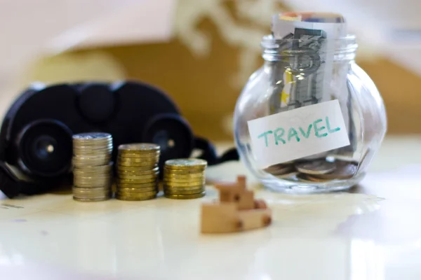 Travel budget - vacation money savings in a glass jar on world m