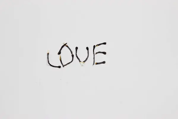 Надпись на горящих спичках: любовь. Белый фон . — стоковое фото
