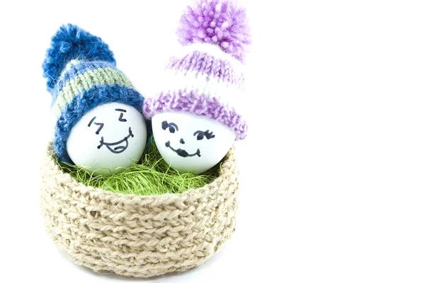 Œufs de Pâques dans un panier. Émoticônes en bonnets tricotés avec pompons — Photo