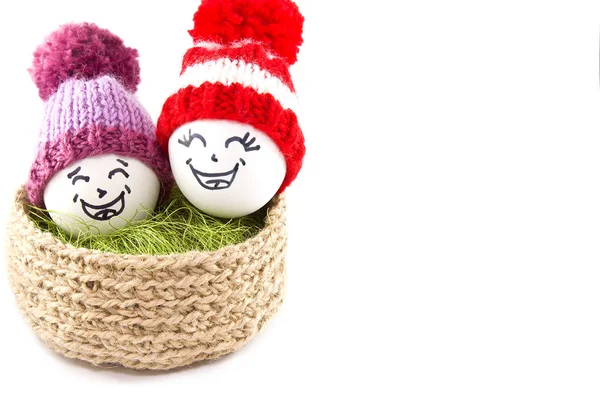 Œufs de Pâques dans un panier. Émoticônes en bonnets tricotés avec pompons — Photo