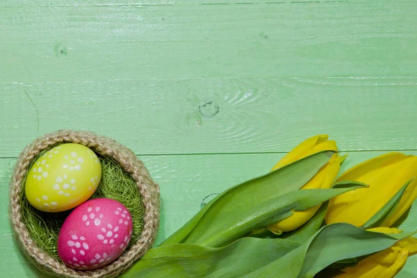 Ostereier in einem Korb. Eier bemalt. ein Strauß gelber Tulpe — Stockfoto