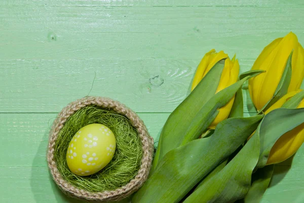 Ostereier in einem Korb. Eier bemalt. ein Strauß gelber Tulpe — Stockfoto