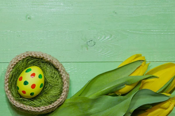 Ostereier in einem Korb. Eier bemalt. ein Strauß gelber Tulpe — Stockfoto