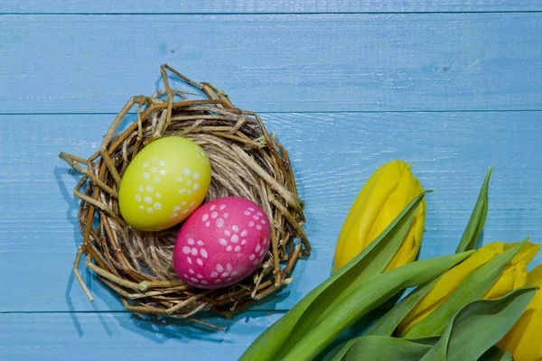 Ostereier im Nest bemalt. ein Strauß gelber Tulpen — Stockfoto