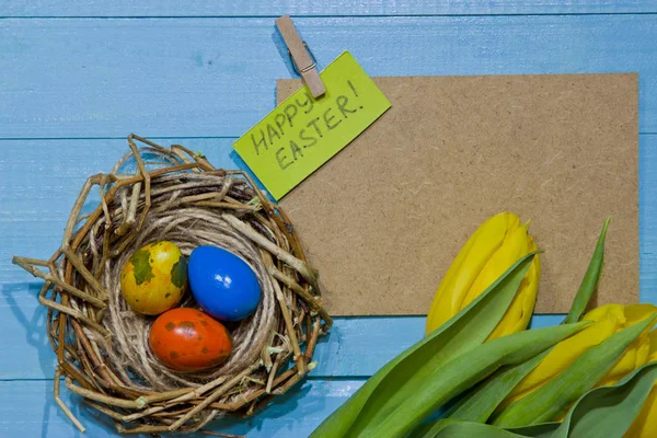 Ostereier im Nest bemalt. ein Strauß gelber Tulpen — Stockfoto