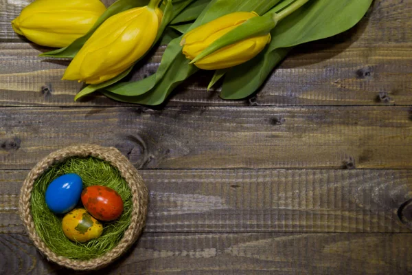 Ostereier bemalt. ein Strauß gelber Tulpen. — Stockfoto