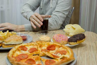 Bir adam bir bilgisayarda çalışıyor ve hızlı yemek yiyor. sağlıksız yiyecek: BÜ