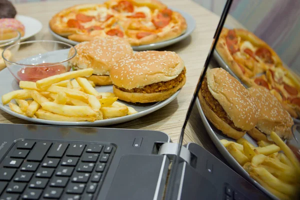 Pracujesz w komputerze i fast food. Niezdrowe jedzenie: Burger, sauc — Zdjęcie stockowe