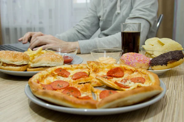 Um homem trabalha num computador e come fast food. alimentos não saudáveis: Bu — Fotografia de Stock