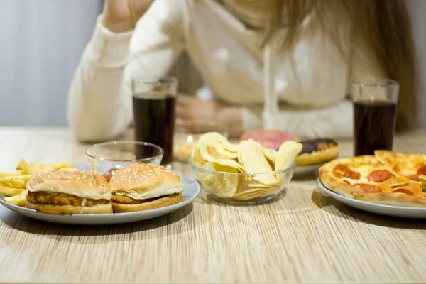 女の子はテーブルに座って、ファーストフードを食べること. — ストック写真