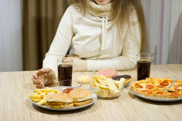 La chica está sentada en la mesa y comiendo comida rápida. . — Foto de Stock