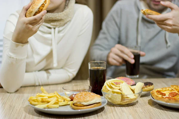 Conceito pouco saudável. Alguns amigos estão sentados à mesa. — Fotografia de Stock