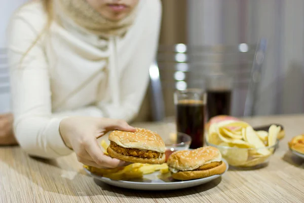 不健康な概念。女の子はテーブルに座って食べたり — ストック写真