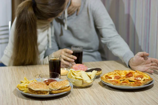 Een paar liefhebbers zitten aan de tafel en eten fastfood. — Stockfoto