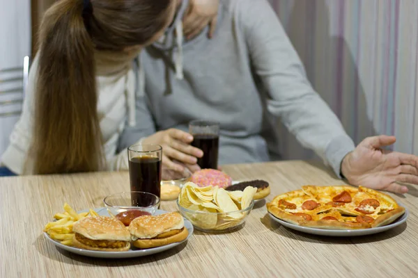 Een paar liefhebbers zitten aan de tafel en eten fastfood. — Stockfoto