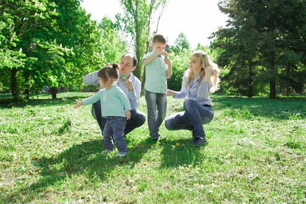 Eine vierköpfige Familie darf Seifenblasen machen. — Stockfoto