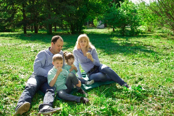 Uma família de quatro comem sorvete ao ar livre . — Fotografia de Stock