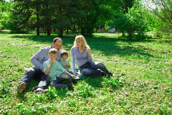 Uma família de quatro comem sorvete ao ar livre . — Fotografia de Stock