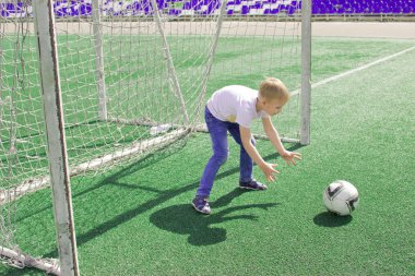 Bir çocuk bir futbol sahası üzerinde bir top ile. 