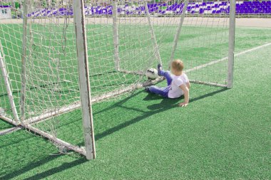 Bir çocuk bir futbol sahası üzerinde bir top ile. 