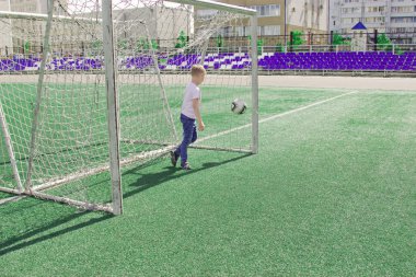 Bir çocuk bir futbol sahası üzerinde bir top ile. 