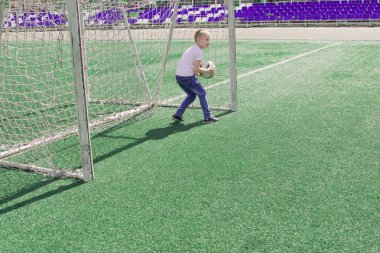 Bir çocuk bir futbol sahası üzerinde bir top ile. 