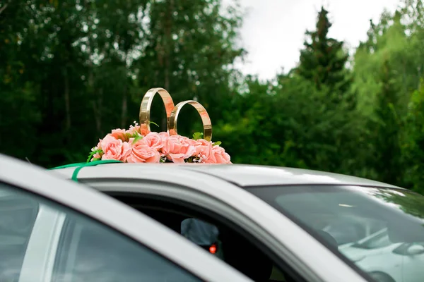 Bagues dorées avec des roses sur la voiture de mariage — Photo