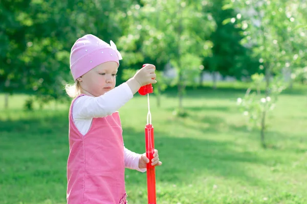 En liten flicka är att lära sig att blåsa bubblor. — Stockfoto