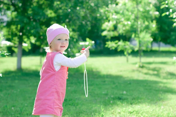 Uma menina está aprendendo a soprar bolhas . — Fotografia de Stock