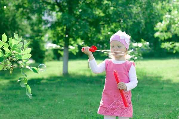 Une petite fille apprend à souffler des bulles . — Photo