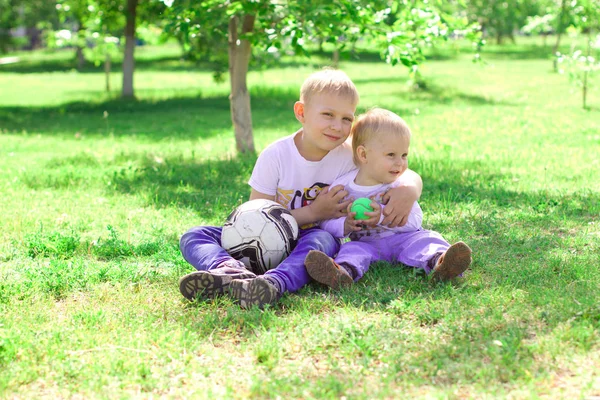 The brother hugs his younger brother in the park. Bright sunny s