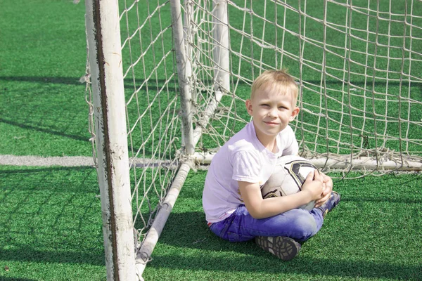 Um rapaz com uma bola num campo de futebol . — Fotografia de Stock