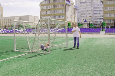 Baba oğlu futbol oynarken yürür. 