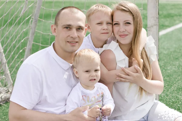 Uma família de quatro num campo de futebol. Brilhante dia de verão ensolarado . — Fotografia de Stock