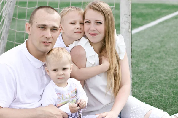 Eine vierköpfige Familie auf einem Fußballplatz. strahlend sonniger Sommertag. — Stockfoto